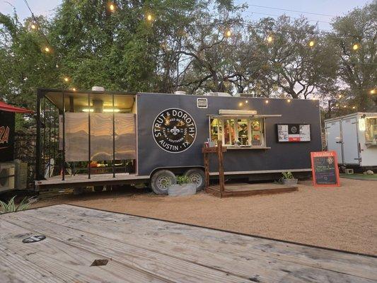 In the food truck area, at the Armadillo Den, due north of the bar.