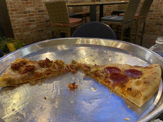 Undercooked pizza crust soaked in grease with puddles on the metal pizza tray