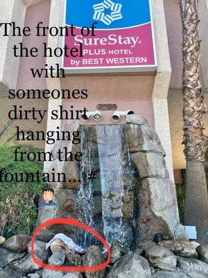 Front of hotel with a dirty shirt hang from fountain.