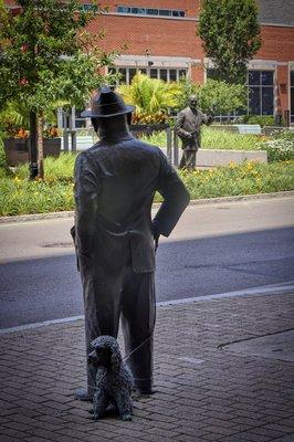 There is a bronze statue of a gentleman waving to the statue of Mr. Brown who is looking directly at that gentleman.