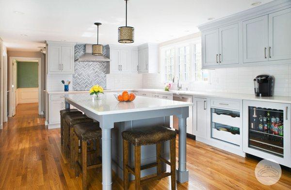 JM Construction renovated this white kitchen with new hardwood flooring, cabinets, and a tile backsplash.