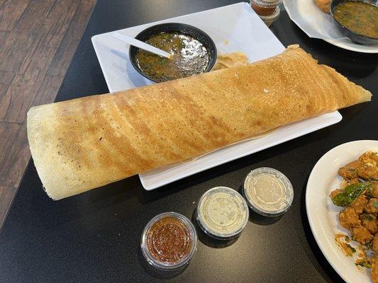 A marsala dosa with sambar and coconut chutney, peanut chutney, tomato chutney