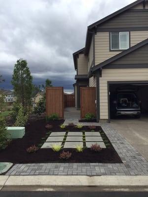 Beautiful pavers from driveway, walkway, to backyard. Ground covering plants near surrounding paver slabs as decorations.