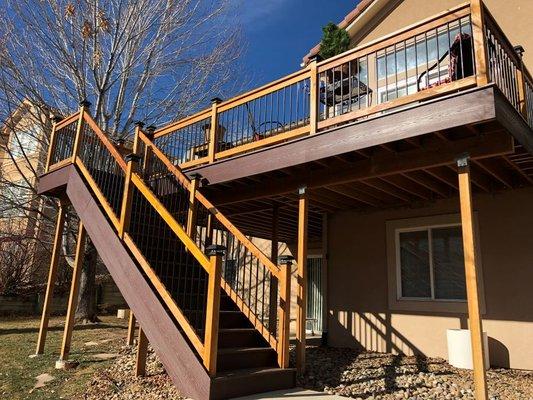 Composite deck with wood railing and iron balusters with built-in lights.