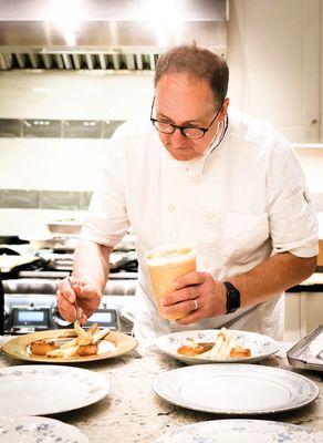 Chef Jonathan plating scallops and asparagus on vintage plates.