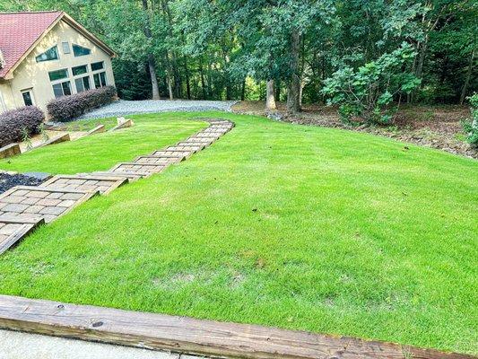 Sod installation and paver steps leading down a sloped backyard.