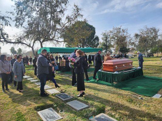 A staff member at Greenlawn Cemetary passing roses to place on coffin