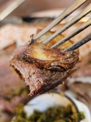 Close-up of a fork with a piece of a potato and The C.A.B. Picahna Steak.