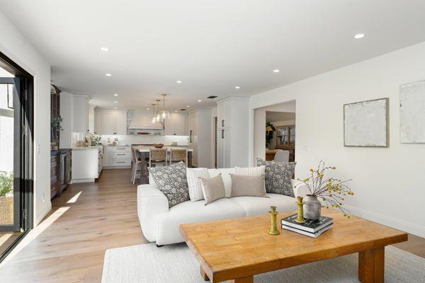 Living room by Blum Remodeling featuring open flow to a modern kitchen with soft neutral tones. A warm, welcoming design.