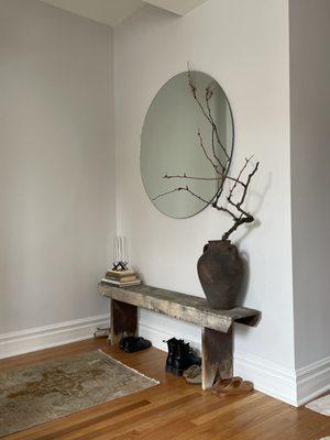 Entryway bench with round mirror hung above