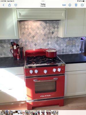 Big Chill red stove, light green cabinets, green marble backsplash.