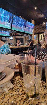 Bartender eating at the bar, serving the uniformed waitstaff alcohol.