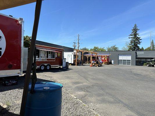 Parking lot. Coffee cart next door. A few wooden picnic tables; about 4 more tables not pictured (behind us).