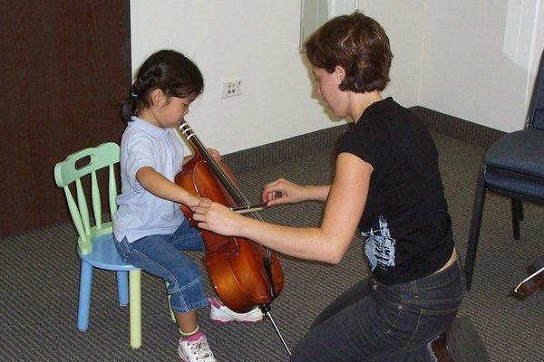 Child playing cello with music teacher