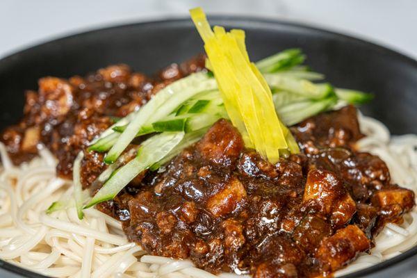 Savory black bean sauce served on top of thick, chewy wheat
noodles and topped with fresh cucumbers and pickled radish