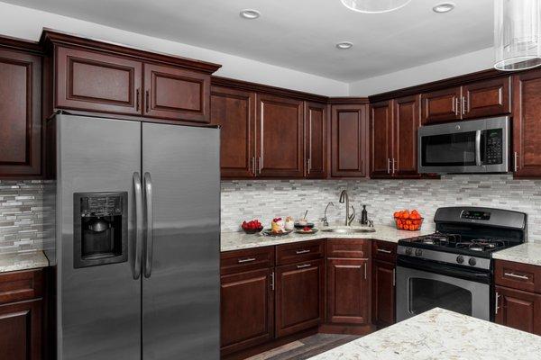 Brown cabinets with light quartz top and subtle back splash tile.