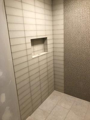 Custom shower with glass tile/mosaic on walls and porcelain flooring with gutter drain.