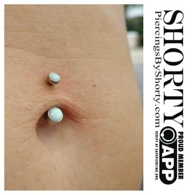 Navel with Industrial Strength titanium navel curve featuring 4mm and 6mm white opal cabochons.