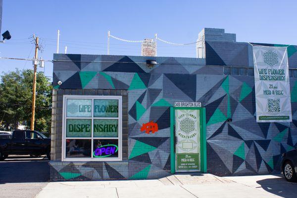 The front of Life Flower RiNo's building with windows, a main door and a vinyl banner hanging.