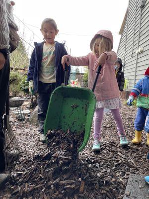 An elementary student and a kindergartener work together in our outdoor classroom