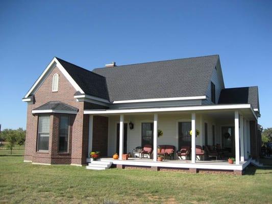 This brick house with wrap-around porch has plenty of wood trim and siding to be painted and protected from the elements.