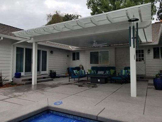 Attached insulated solid patio cover, equipped with a fan, and lattice trim on three sides.