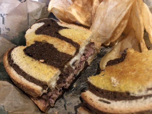 Fried French onion burger on grilled marble rye with chips