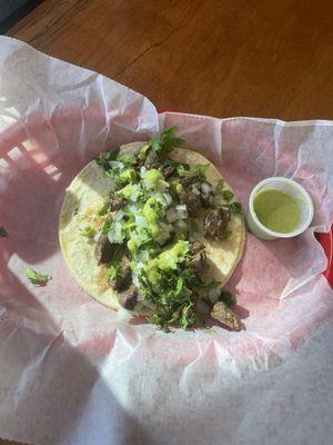 Carne asada taco on corn tortilla with cilantro, onion, and salsa.