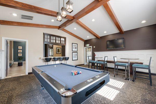 Carpeted clubhouse with pool table, high tables and chairs, and TV.