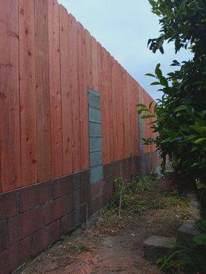 Wood fence rebuilt with cinder blocks & cement with rebar.