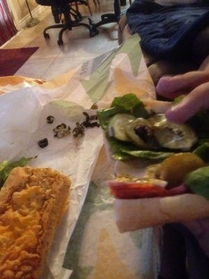 This photo is my boyfriend picking olives off his sandwhich after we tries to tell the sandwhich maker to not put olives on the sandwhich.