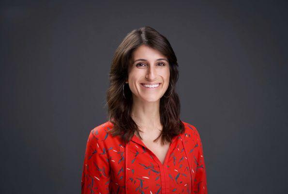 Bold corporate headshot in a vibrant outfit against a charcoal gray backdrop with dramatic shadows. Taken by 415Headshots.