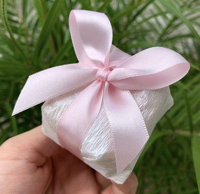 A charming 'bem casado' in delicate crepe paper with a satin ribbon. Inside, a soft sponge cake filled with sweet dulce de leche awaits.