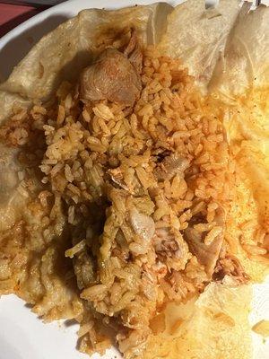 The burrito is filled with rice in this close up shot and just a few pieces of chicken