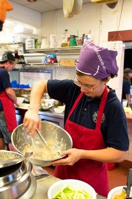 Kitchen Coordinator Randi B. Hagi folding pasta into a primavera sauce.