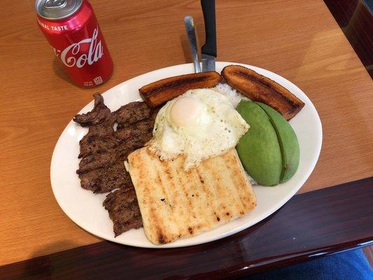 Grilled steak rice egg avocado sweet plantain and arepa witch is a grilled corn cheese bread