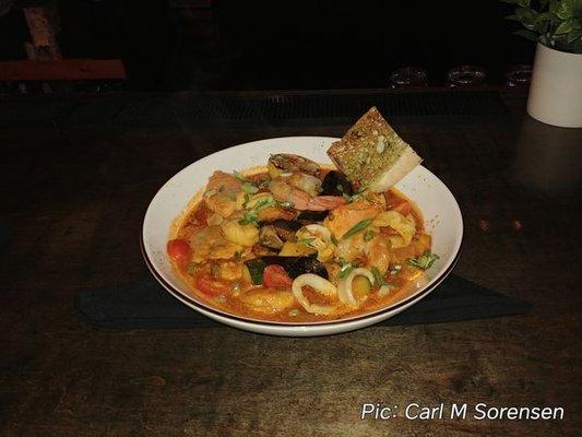 Cioppino, consisting of a saffron tomato broth, shrimp, calamari, muscles, salmon, and sea bass.