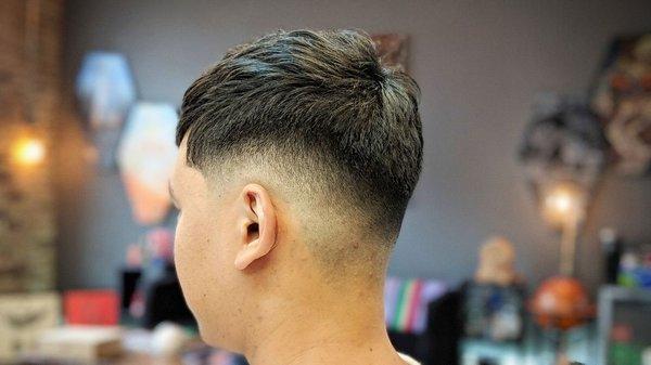 Low/mid razor fade with texture on top. Haircut done by Brian