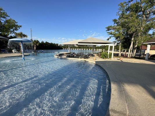 Pool/splash pad in front of lake.