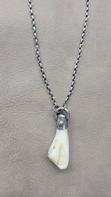 A custom necklace created from sterling silver and a Bison tooth .