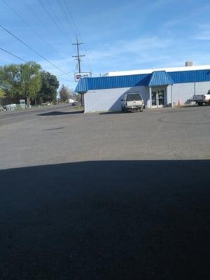 In the auto parts parking lot with the building with the blue trim roof