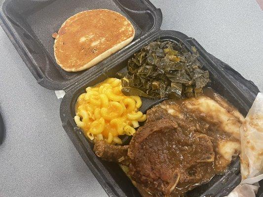 The smothered pork chop dinner with 2 Smothered Pork Chops, mashed potatoes, mac and cheese, and collard greens, and corn bread.