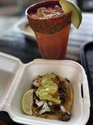 Carne asada taco with habanero sauce and a Michelada with cucumber Chamoy rim