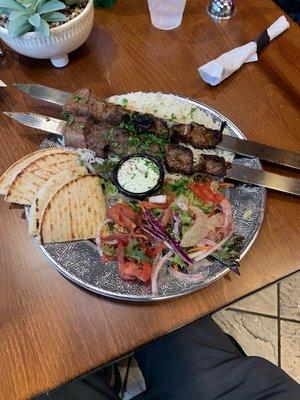 Lamb kabob with salad and pitas,