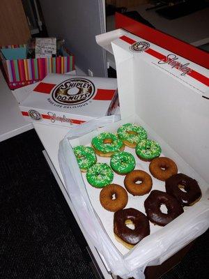 Chocolate iced, green iced, and cake (plain and iced) donut with kolaches in closed box.