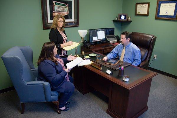 Attorneys Josh Berkley, Amy Oliver, and paralegal Stephanie Smith discussing a case.