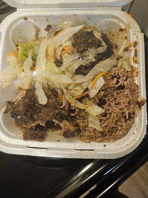 Half eaten jerk chicken, rice and peas and cabbage