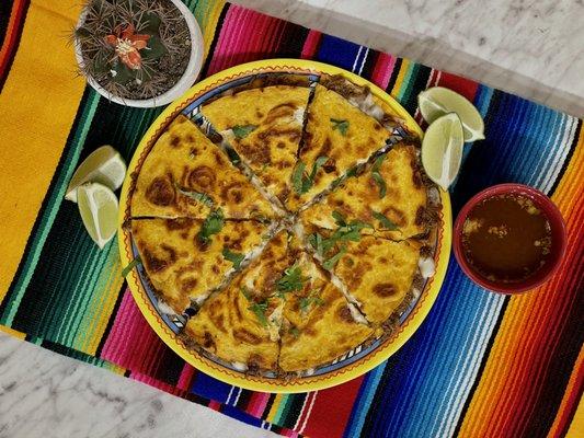 Quesabirria! Pizza-like quesadilla, stuffed with our homemade Barbacoa, cheese, cilantro and onions! Accompanied with a side of Consume!