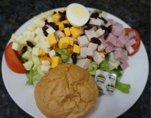 A fresh and colorful Cobb salad featuring greens, hard-boiled eggs, diced ham, and creamy dressing is available for dine-in o...