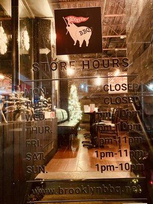 Restaurant entrance door with hours of operation.